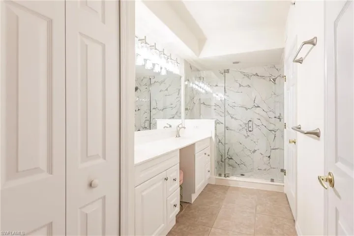 Bathroom with tile patterned flooring, an enclosed shower, and vanity