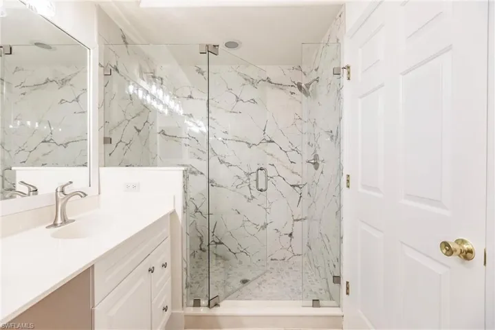 Bathroom featuring a shower with door and vanity