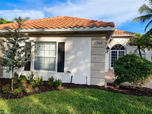 View of side of property with a tile roof, stucco siding, and a lawn
