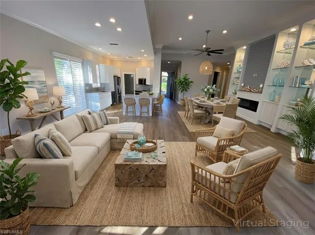 Living room featuring ornamental molding, wood finished floors, a fireplace, healthy amount of natural light, and built in features