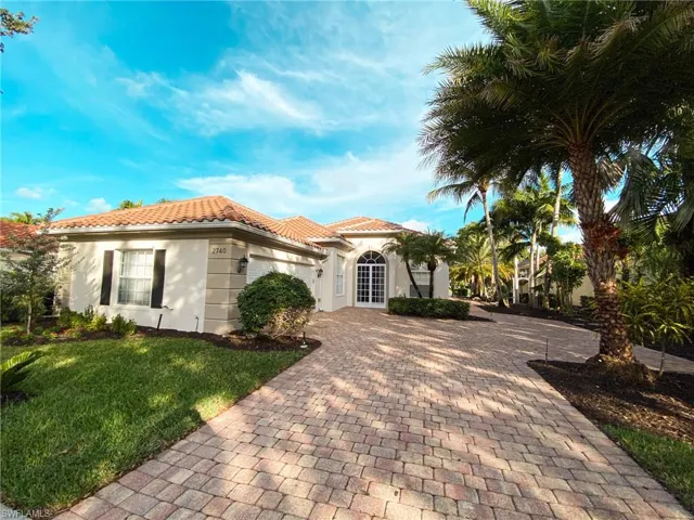 Mediterranean / spanish house with decorative driveway, stucco siding, a front lawn, a tile roof, and a garage
