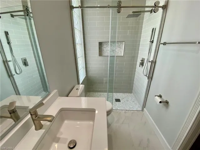 Bathroom with a stall shower, vanity, and light marble finish floors
