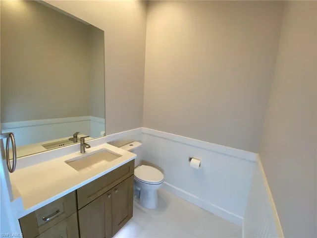 Bathroom with a wainscoted wall, vanity, a decorative wall, and light tile patterned flooring