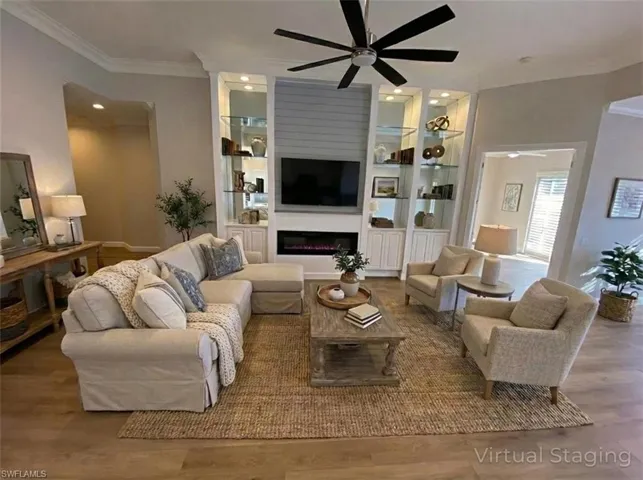 Living area with crown molding, wood finished floors, a warm lit fireplace, ceiling fan, and recessed lighting