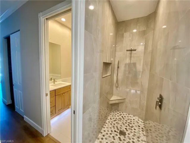 Full bathroom with vanity, a walk in shower, wood finished floors, and recessed lighting