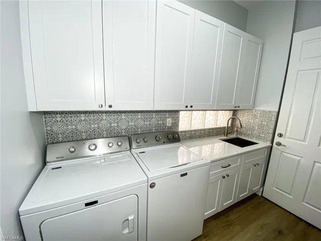 Laundry area featuring washing machine and dryer, cabinet space, and dark wood-type flooring