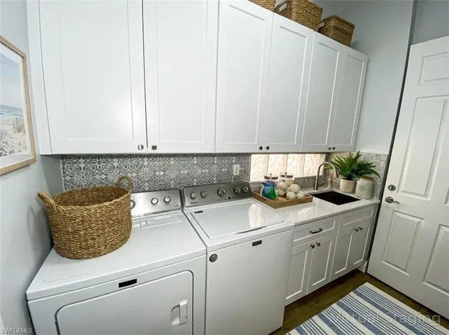 Washroom with washing machine and dryer, dark wood finished floors, and cabinet space