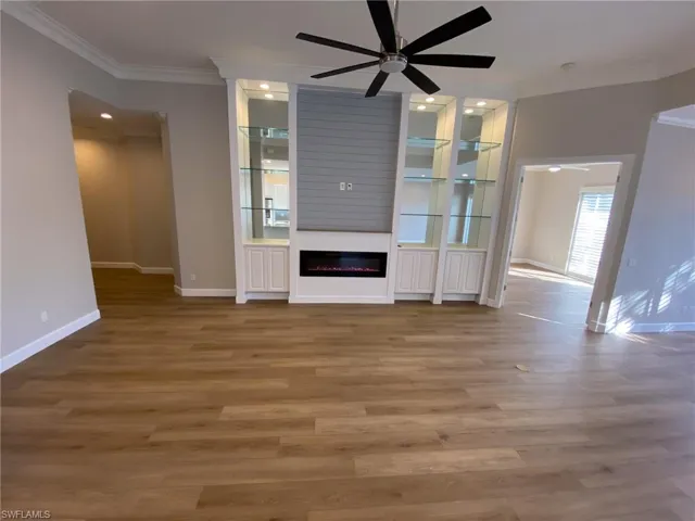 Unfurnished living room with ornamental molding, wood finished floors, ceiling fan, a fireplace, and recessed lighting