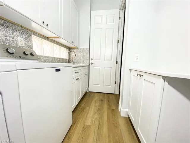 Laundry room with washer / clothes dryer, light wood finished floors, and cabinet space