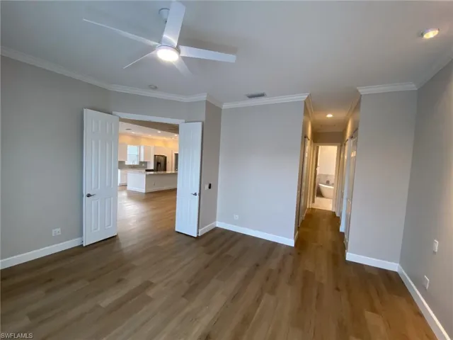 Unfurnished bedroom featuring dark wood-style flooring, recessed lighting, stainless steel fridge with ice dispenser, crown molding, and a ceiling fan