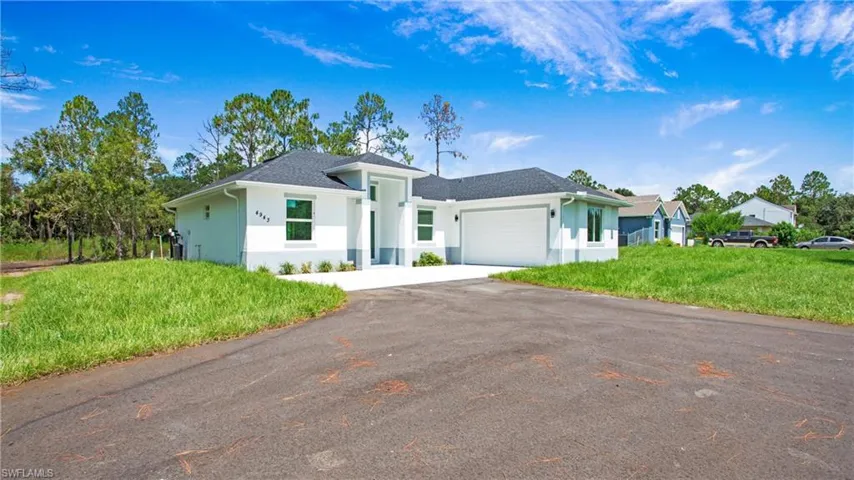 View of front of house featuring driveway, a garage, stucco siding, and a front yard