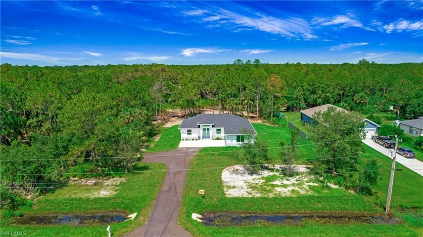 Aerial view of property and surrounding area with a heavily wooded area