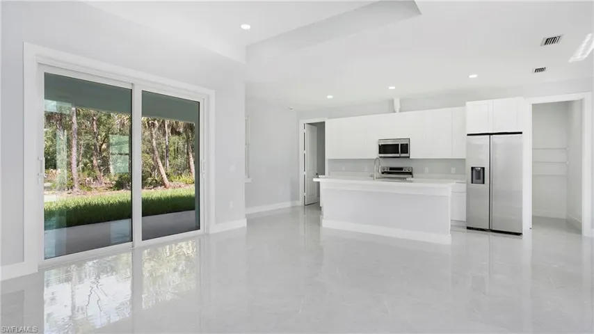 Kitchen with stainless steel appliances, light countertops, white cabinetry, and recessed lighting