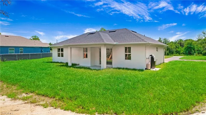 Back of property featuring stucco siding, a shingled roof, and a patio area