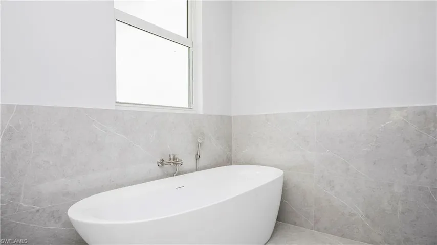 Full bath featuring a freestanding tub, a wainscoted wall, and tile walls