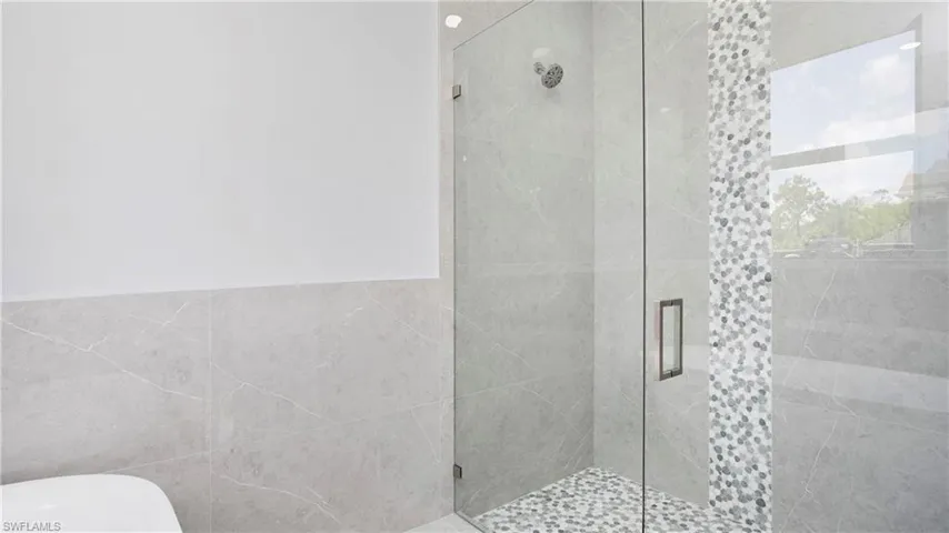 Full bathroom featuring a stall shower, tile walls, and a soaking tub