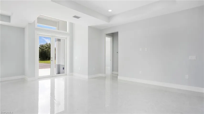 Empty room featuring a raised ceiling, recessed lighting, and french doors