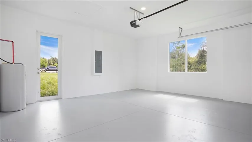 Garage featuring water heater, electric panel, and a garage door opener