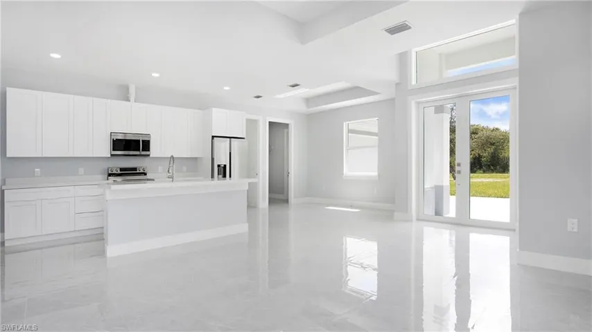 Kitchen featuring stainless steel appliances, a center island with sink, white cabinets, and recessed lighting