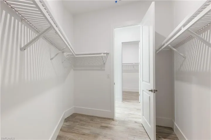 Spacious walk in closet with light hardwood / wood-style flooring