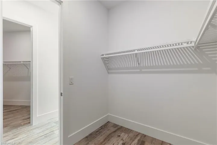 Walk in closet with light hardwood / wood-style floors