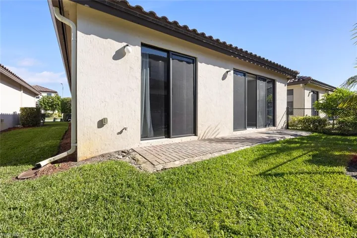 Rear view of property with a patio area, stucco siding, a yard, and fence