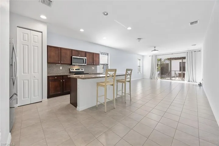 Kitchen with light tile patterned floors, visible vents, appliances with stainless steel finishes, open floor plan, and backsplash
