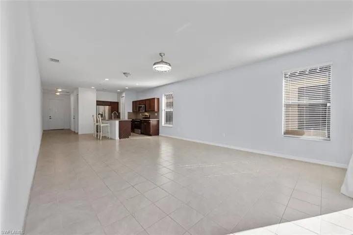 Unfurnished living room featuring visible vents, a sink, recessed lighting, light tile patterned floors, and baseboards