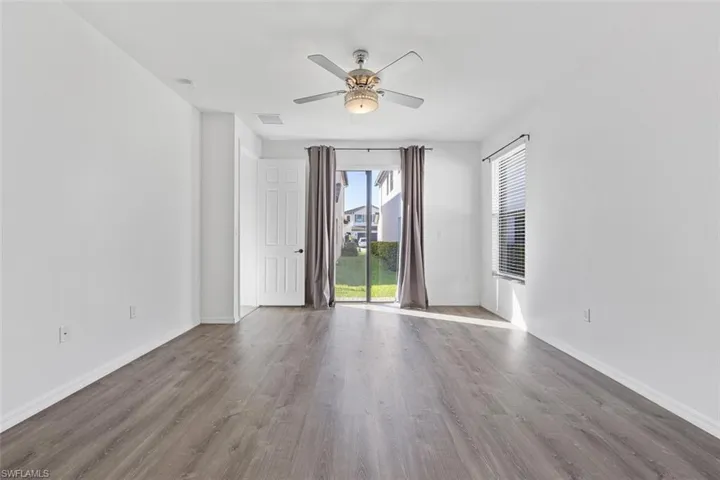Empty room with a ceiling fan, wood finished floors, visible vents, and baseboards