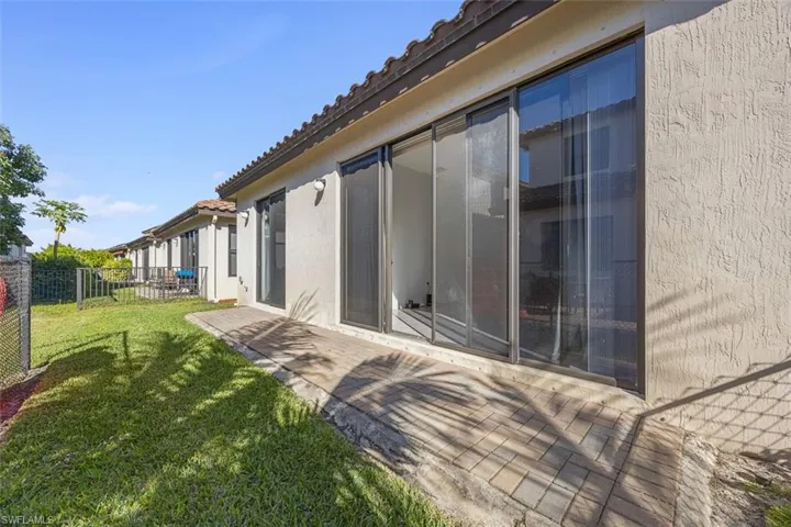 Rear view of house with a patio, fence, stucco siding, a tiled roof, and a lawn