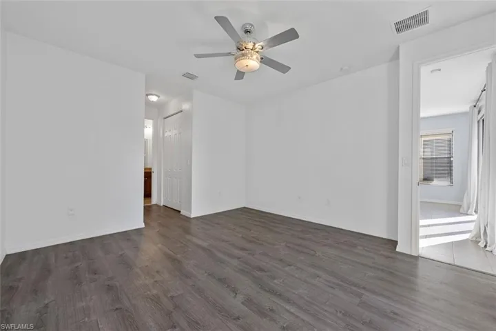 Empty room with visible vents, a ceiling fan, and dark wood-style flooring