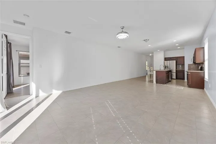 Unfurnished living room with visible vents, recessed lighting, baseboards, and a sink