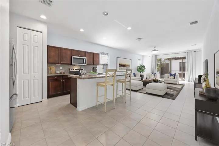 Virtually Staged-Kitchen with visible vents, a breakfast bar, tasteful backsplash, open floor plan, and stainless steel appliances