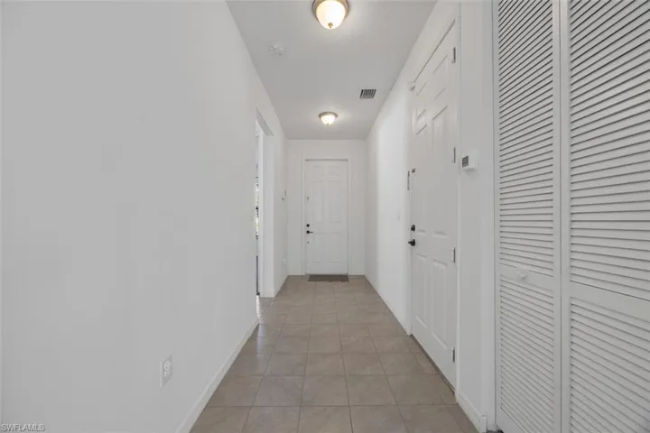 Hallway featuring light tile patterned floors, visible vents, and baseboards
