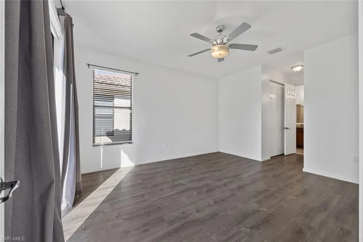 Spare room featuring visible vents, baseboards, dark wood-type flooring, and ceiling fan
