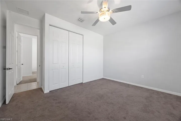 Unfurnished bedroom featuring a closet, visible vents, a ceiling fan, and carpet floors