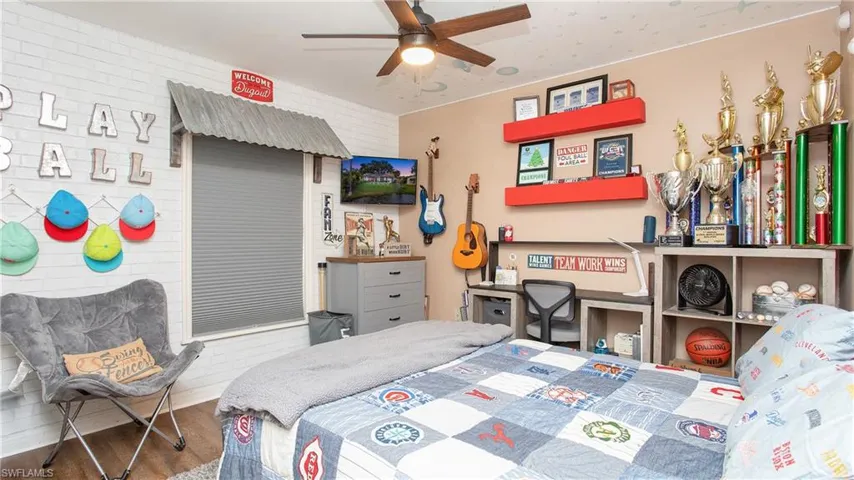 Bedroom with wood-type flooring, brick wall, and ceiling fan