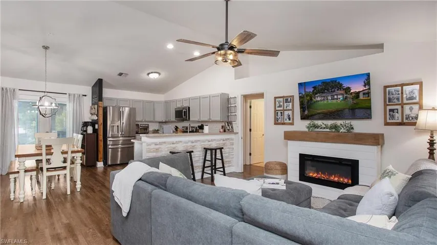 Living room featuring ceiling fan with notable chandelier, lofted ceiling, and dark hardwood / wood-style floors