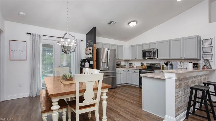 Kitchen with pendant lighting, a breakfast bar, a chandelier, kitchen peninsula, and stainless steel appliances