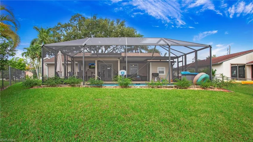 Rear view of property with a lawn, glass enclosure, and a patio area