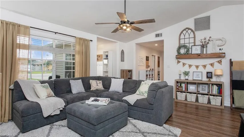 Living room featuring vaulted ceiling, ceiling fan, and hardwood / wood-style flooring