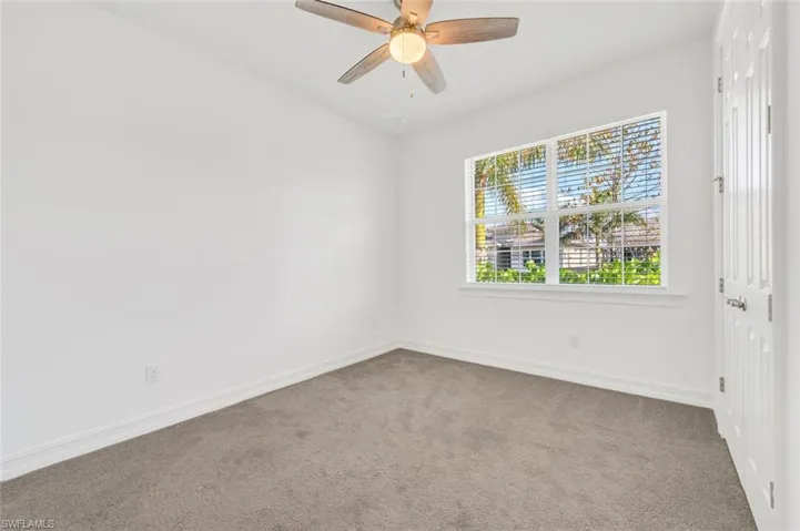 Carpeted spare room with baseboards and a ceiling fan