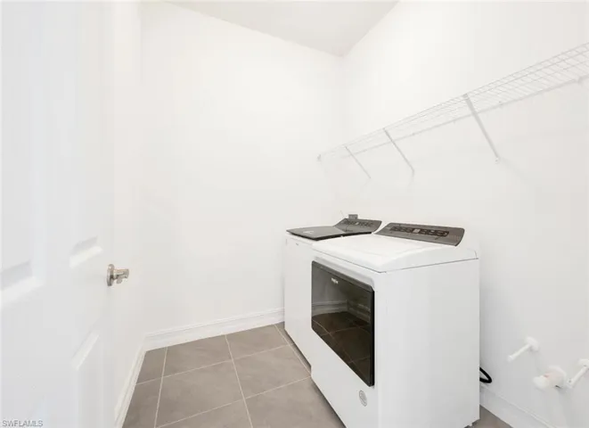 Washroom with light tile patterned flooring and washer and clothes dryer
