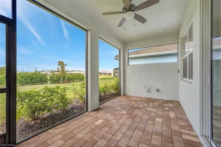 Unfurnished sunroom featuring brick floors, a ceiling fan, and a textured wall