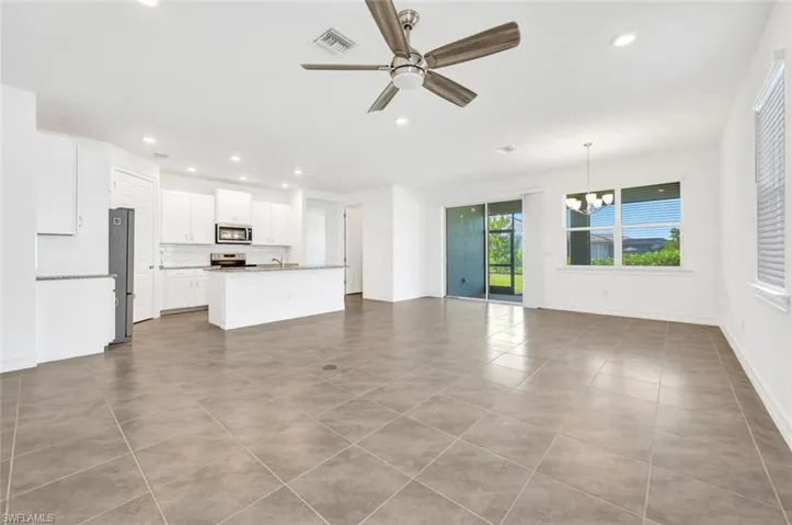 Unfurnished living room featuring ceiling fan, recessed lighting, light tile patterned floors, and a chandelier