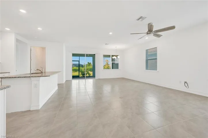 Unfurnished living room featuring recessed lighting, ceiling fan, light tile patterned floors, and a chandelier