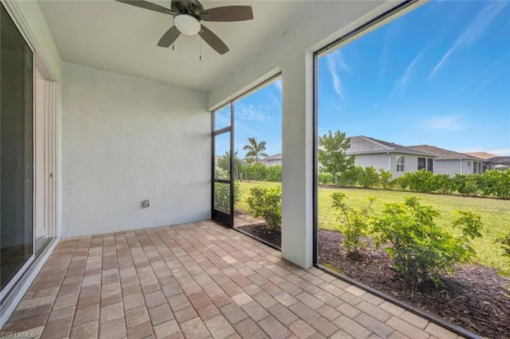 Unfurnished sunroom featuring a textured wall, brick floors, and ceiling fan