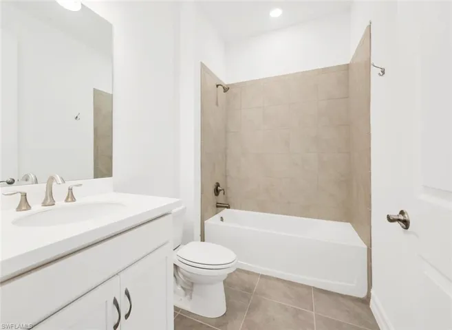 Bathroom with vanity, bathing tub / shower combination, and light tile patterned floors