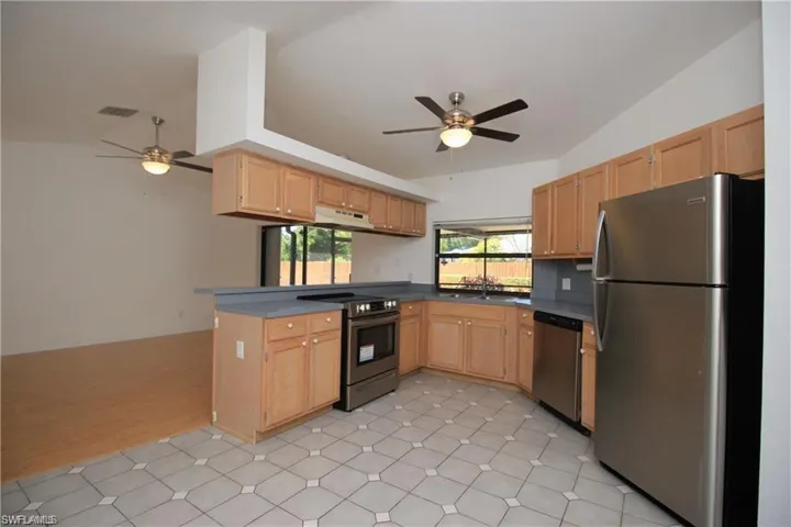 Kitchen featuring light tile floors, ceiling fan, vaulted ceiling, and stainless steel appliances
