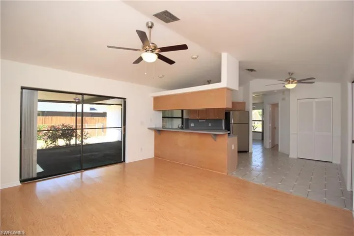 Unfurnished living room featuring ceiling fan, lofted ceiling, and light wood-type flooring